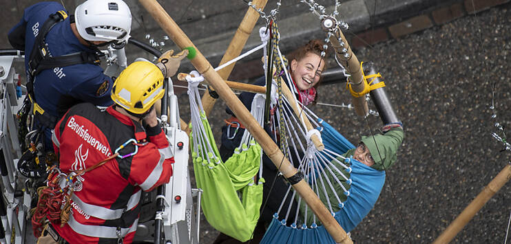 Klima-Aktivistinnen haben sich auf einem Holzgerüst angekettet - sie werden von Höhenrettern von Schutz & Rettung Zürich auf den Boden zurückgeholt. (Bild: KEYSTONE/ENNIO LEANZA)